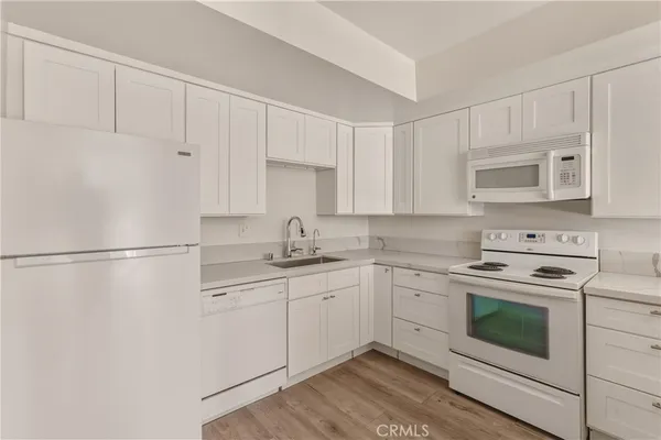 a kitchen with granite countertop white cabinets and white appliances