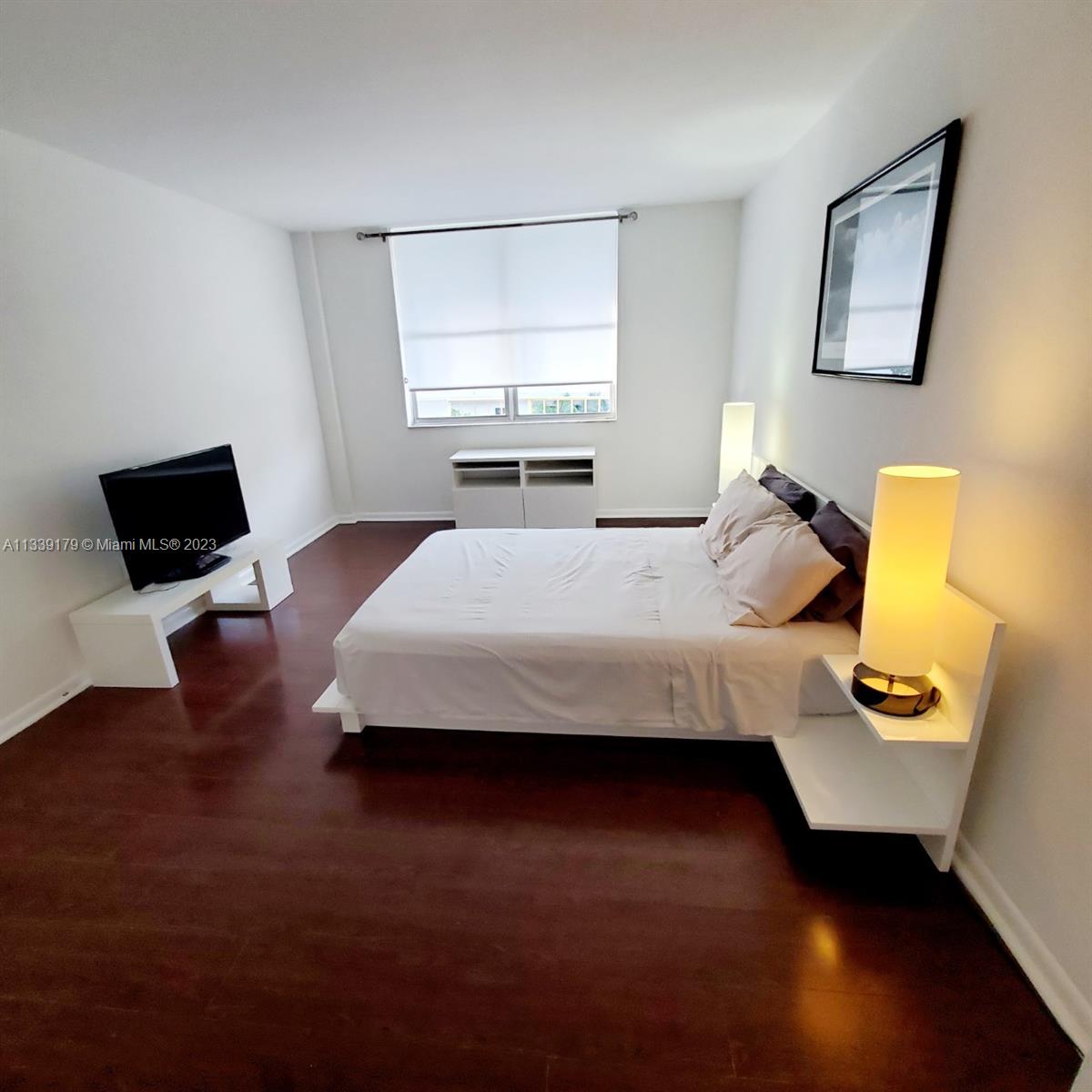 245 18th Street, Unit 403 Miami Beach, FL 33139 - Photo 14 of 30 a bedroom with a bed tv and wooden floor