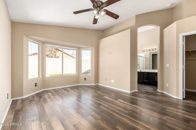a view of an empty room with a window and wooden floor