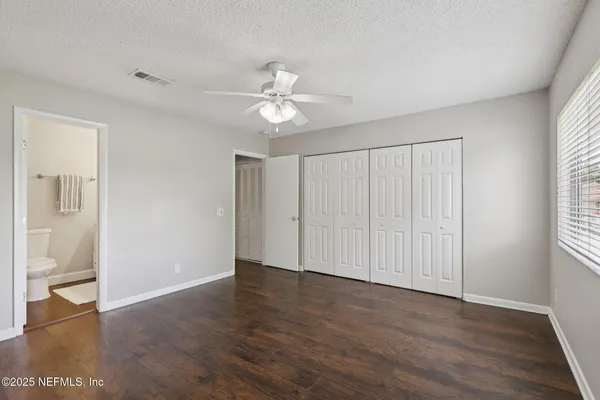 an empty room with wooden floor chandelier fan and windows