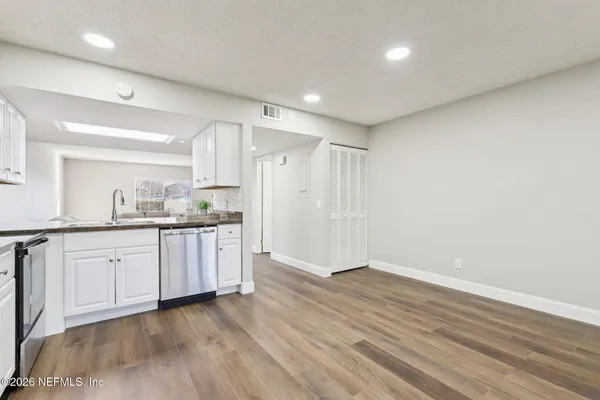 a kitchen with stainless steel appliances a dining table chairs stove refrigerator and cabinets