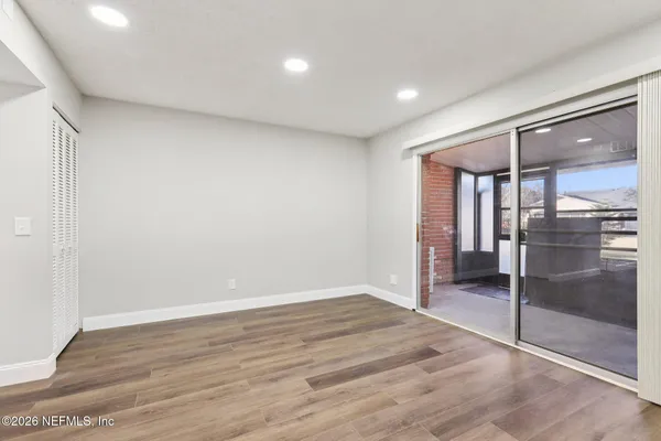 an empty room with wooden floor fan and windows