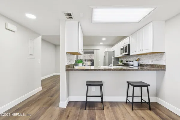 a kitchen with stainless steel appliances granite countertop a white cabinets and wooden floor
