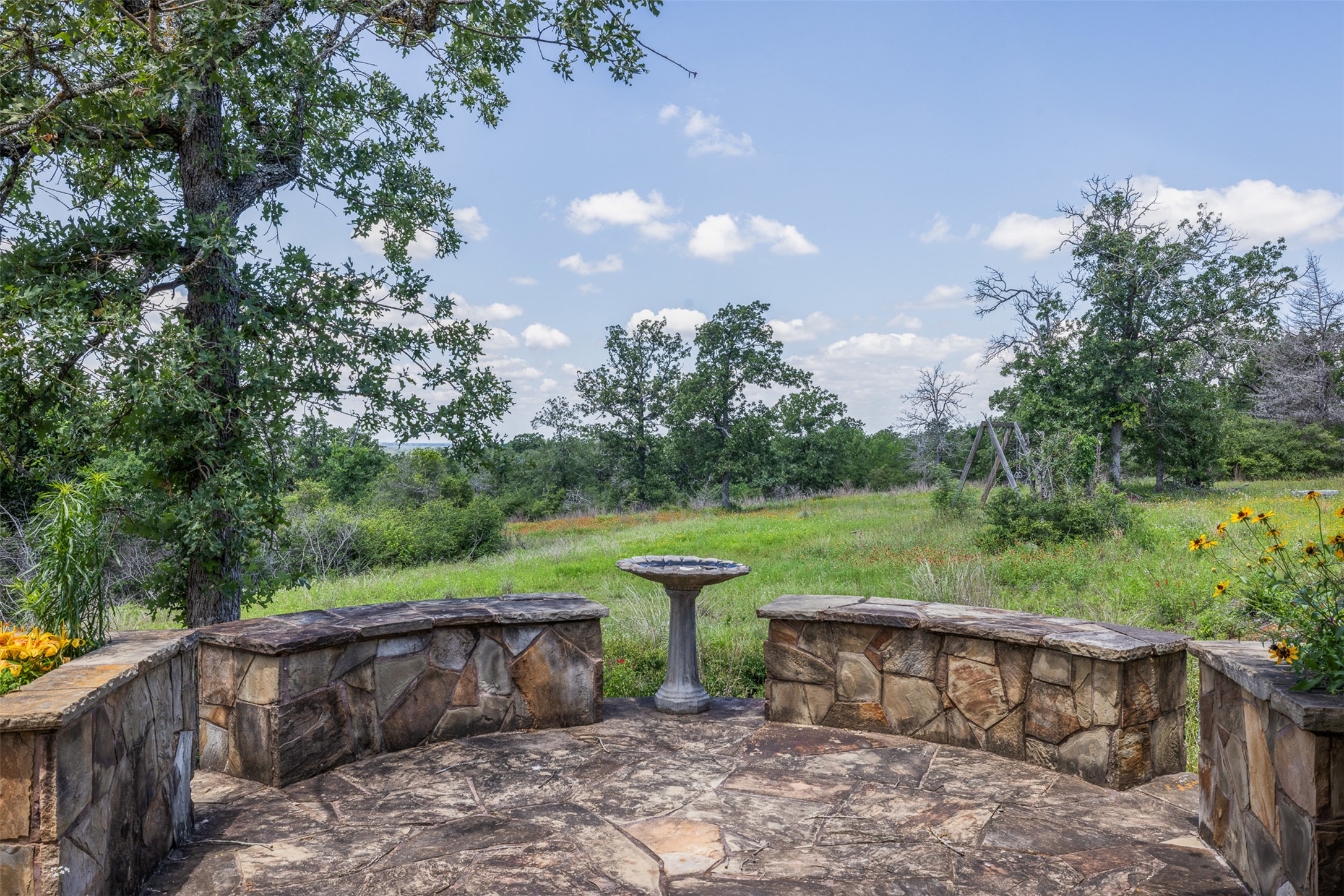 1004 22 Hills Road Gause, TX 77857 - Photo 13 of 37 A stone-paved patio area offers serene views of the surrounding natural landscape and mature trees.
