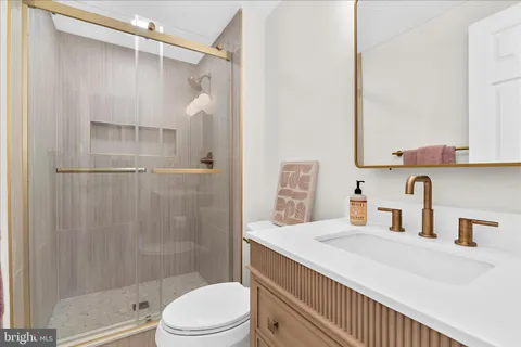 a bathroom with a sink vanity granite toilet and shower