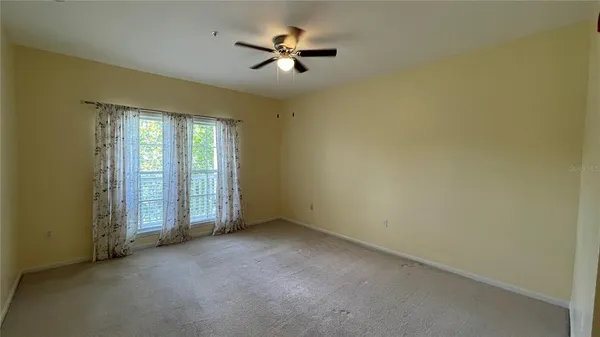 an empty room with a ceiling fan and window