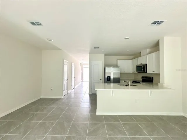 a view of kitchen with refrigerator cabinets and window