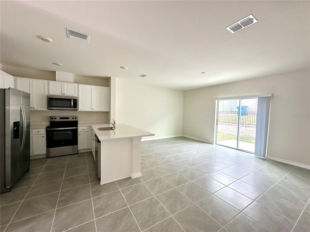 2742 Puffin Place Davenport, FL 33837 - Photo 14 of 31 a kitchen with a refrigerator a sink and a counter top space