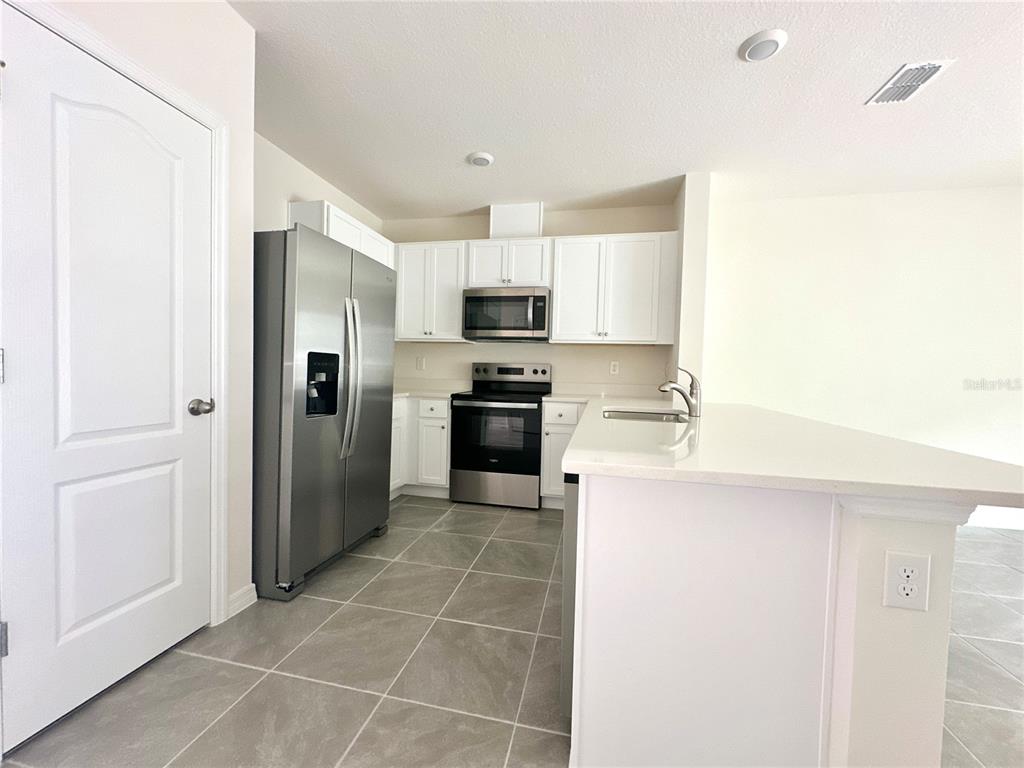 2742 Puffin Place Davenport, FL 33837 - Photo 6 of 31 a kitchen with granite countertop a refrigerator and a stove top oven