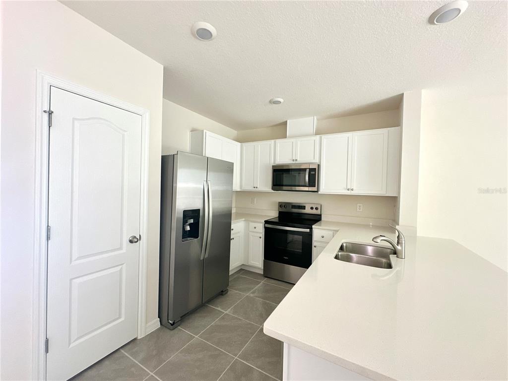 2742 Puffin Place Davenport, FL 33837 - Photo 7 of 31 a kitchen with stainless steel appliances a refrigerator sink and stove