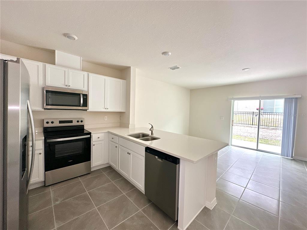 2742 Puffin Place Davenport, FL 33837 - Photo 10 of 31 a kitchen with a sink stove and refrigerator