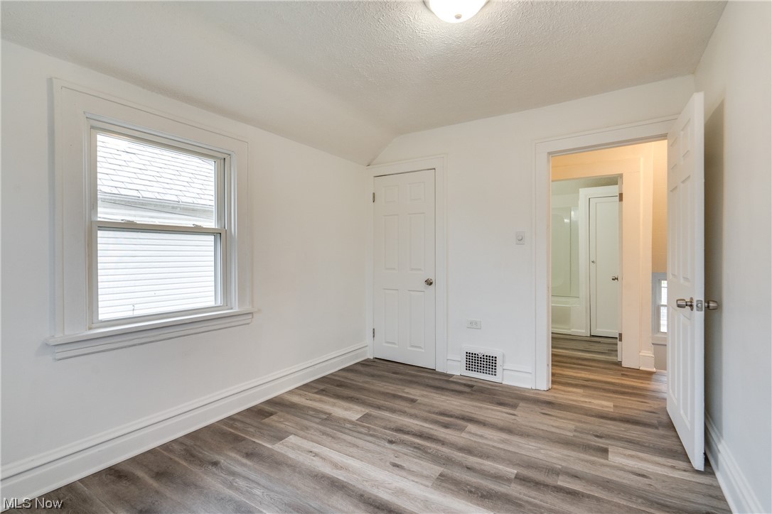 3219 Arbor Road Southwest Canton, OH 44710 - Photo 13 of 15 Spare room with dark wood-type flooring, a textured ceiling, and vaulted ceiling