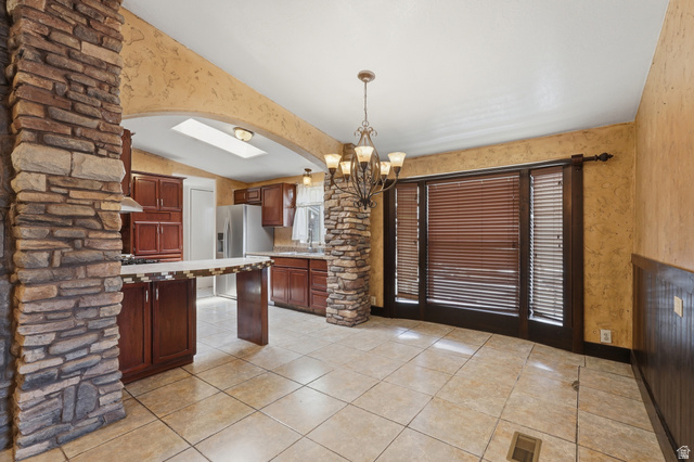 2875 North Hill Field Road, Unit 111 Layton, UT 84041 - Photo 5 of 30 Kitchen featuring light countertops, suspended lighting, a peninsula, stainless steel fridge, and a breakfast bar