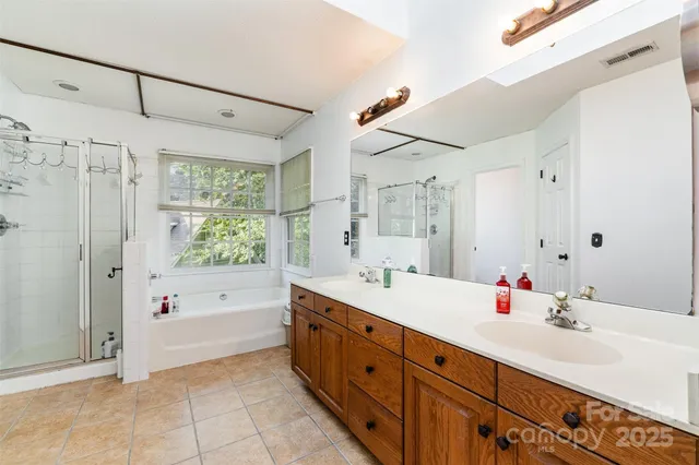 a spacious bathroom with a double vanity sink a large mirror and shower