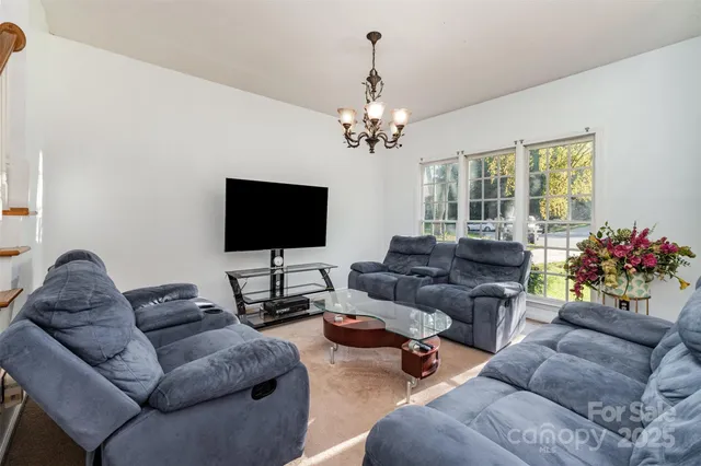 a living room with furniture a flat screen tv and a chandelier