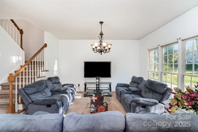 a living room with furniture a flat screen tv and a chandelier