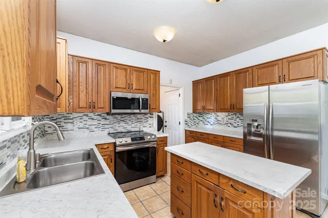 a kitchen with stainless steel appliances granite countertop a stove refrigerator sink and microwave