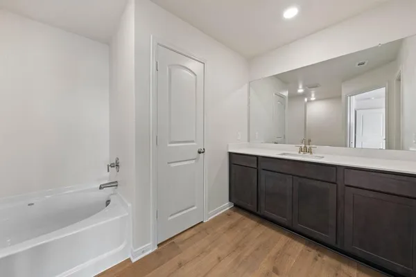 a bathroom with a tub sink and mirror