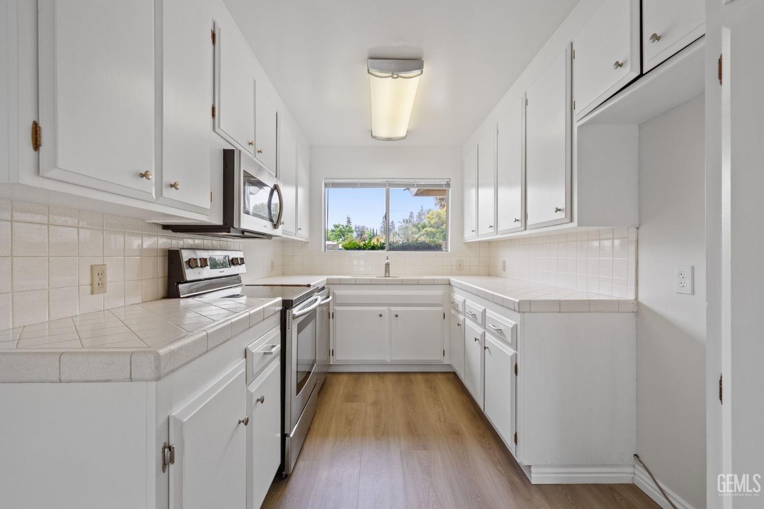Undisclosed Address Bakersfield, CA 93306 - Photo 18 of 46 a kitchen with granite countertop white cabinets and white appliances