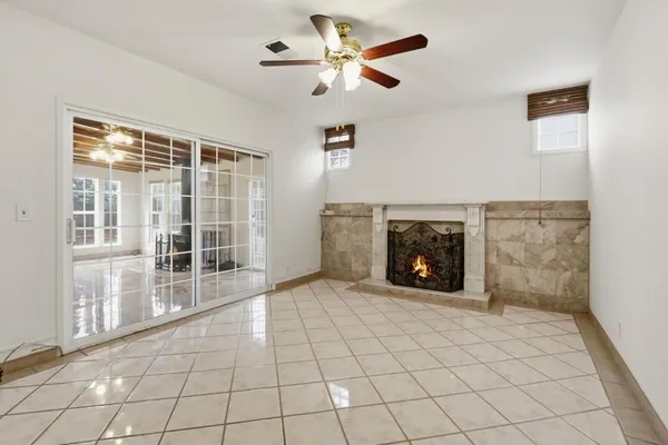 a view of a livingroom with a fireplace a ceiling fan and window
