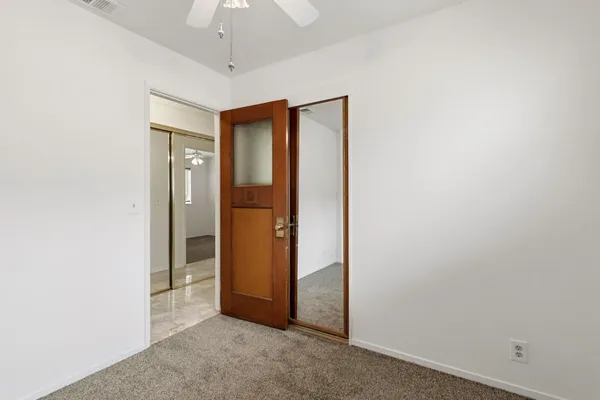 an empty room with closet and a chandelier fan