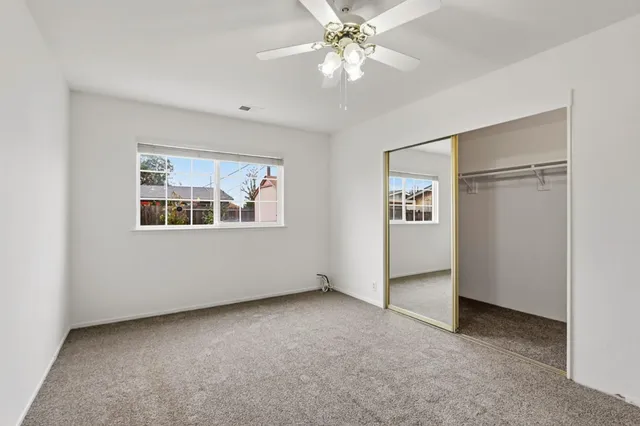 an empty room with windows and ceiling fan
