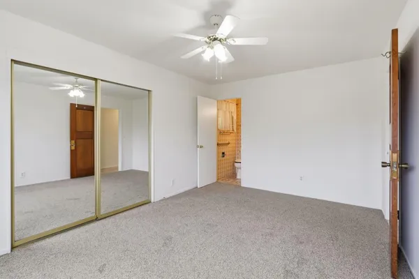 an empty room with closet and a ceiling fan