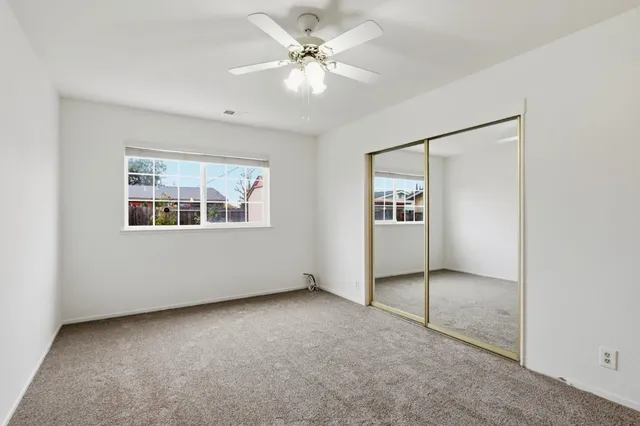 an empty room with chandelier fan and windows