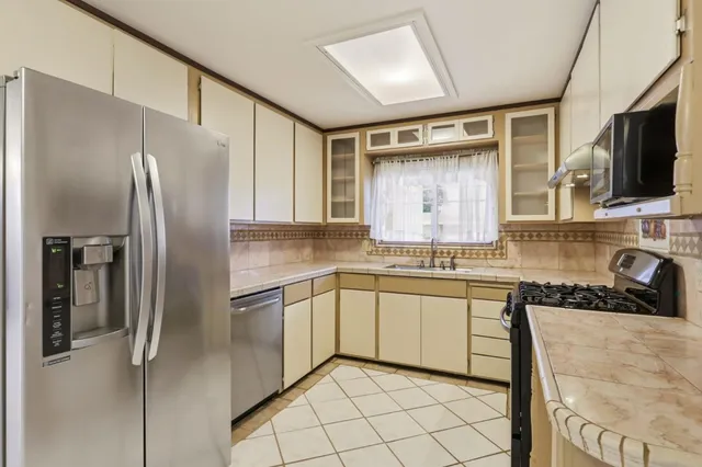 a kitchen with granite countertop a sink stainless steel appliances and cabinets