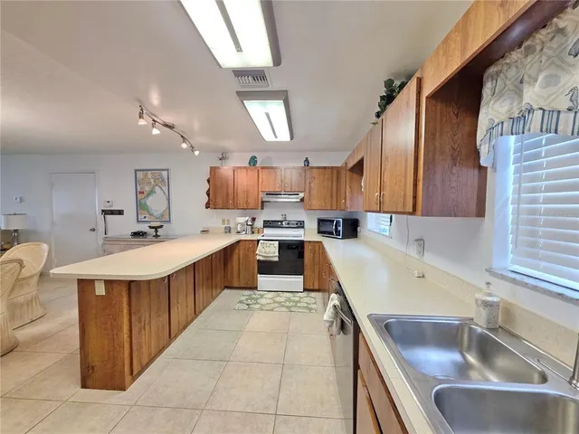 a large kitchen with a large counter top space a sink stainless steel appliances and cabinets