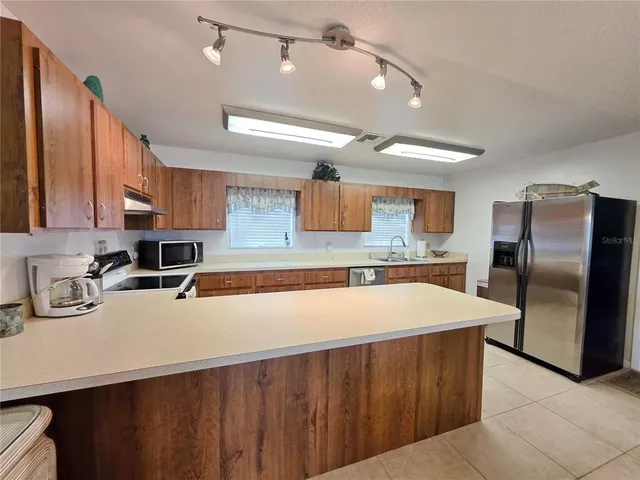 a kitchen with stainless steel appliances a sink a stove a refrigerator cabinets and a counter top space