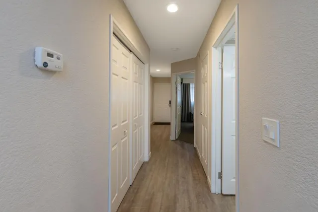 a view of a hallway with wooden floor and a bathroom