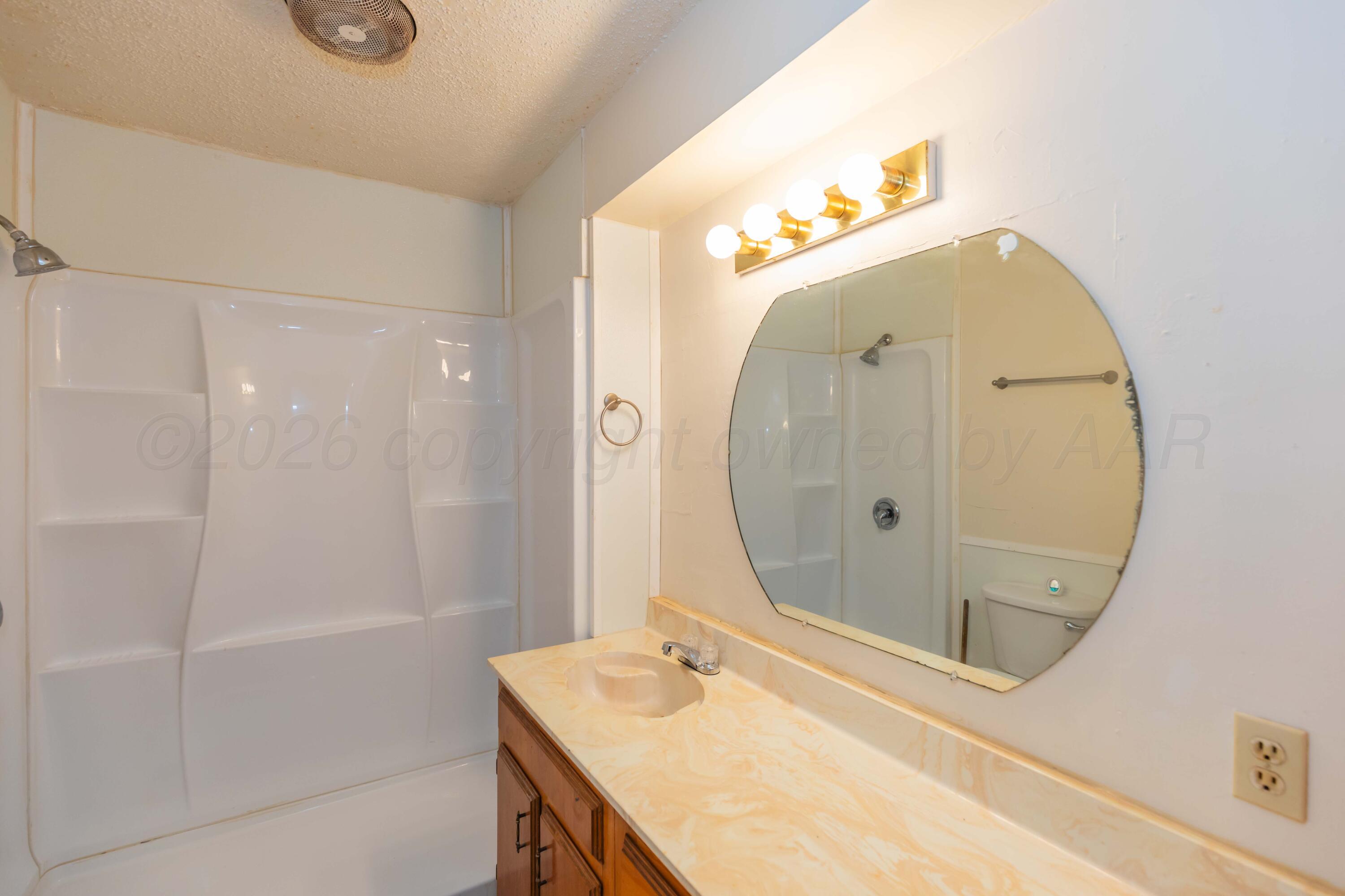 200 South Wall Street Shamrock, TX 79079 - Photo 25 of 40 a bathroom with a sink a mirror and a shower