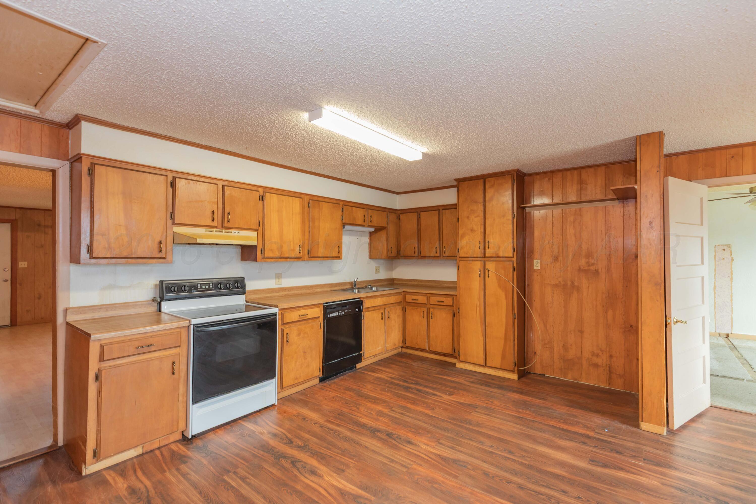 200 South Wall Street Shamrock, TX 79079 - Photo 8 of 40 a kitchen with stainless steel appliances granite countertop a stove a sink dishwasher a refrigerator with white cabinets and wooden floor
