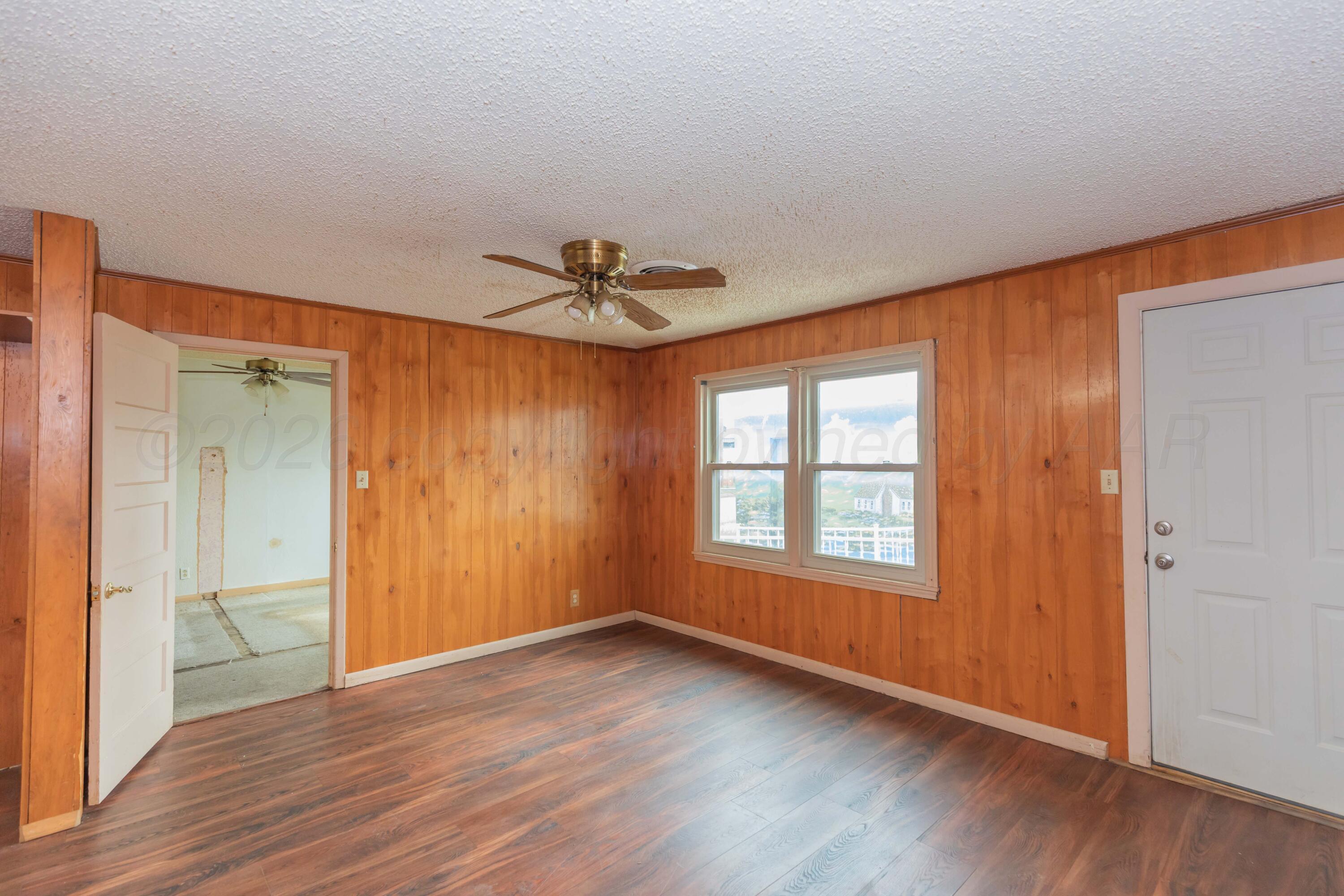 200 South Wall Street Shamrock, TX 79079 - Photo 10 of 40 an empty room with wooden floor chandelier fan and windows