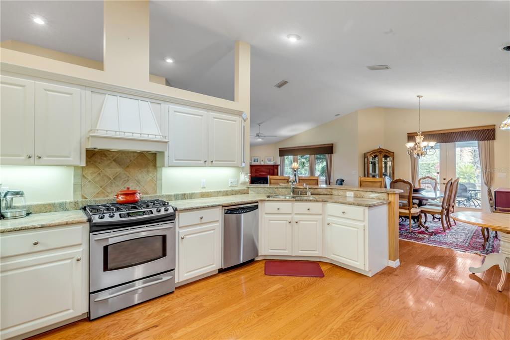 1098 Red Maple Way New Smyrna Beach, FL 32168 - Photo 22 of 78 a kitchen with a stove a sink and white cabinets with wooden floor