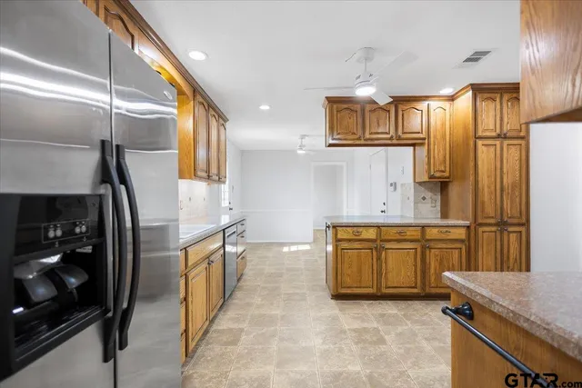 a large kitchen with stainless steel appliances granite countertop a refrigerator and a stove top oven