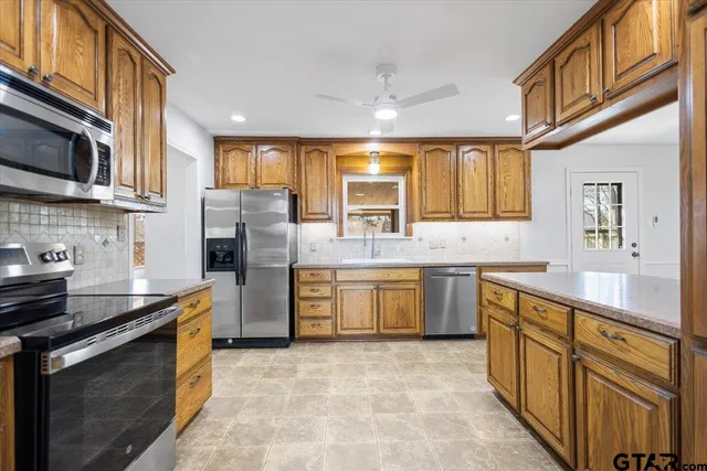 a kitchen with stainless steel appliances granite countertop a stove a sink dishwasher a refrigerator and a microwave