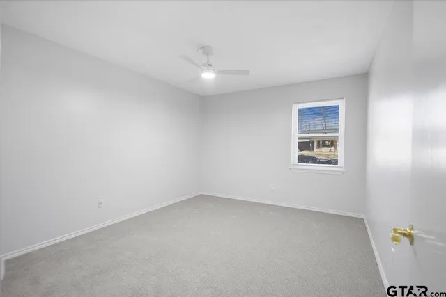 an empty room with windows and ceiling fan