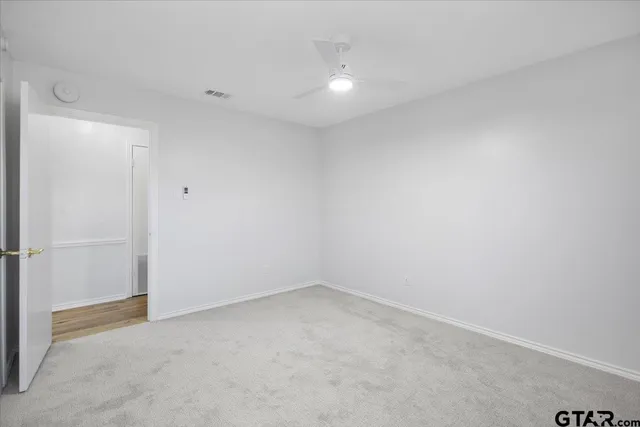an empty room with a window and ceiling fan