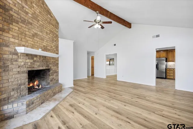 a view of an empty room with wooden floor fireplace and a window
