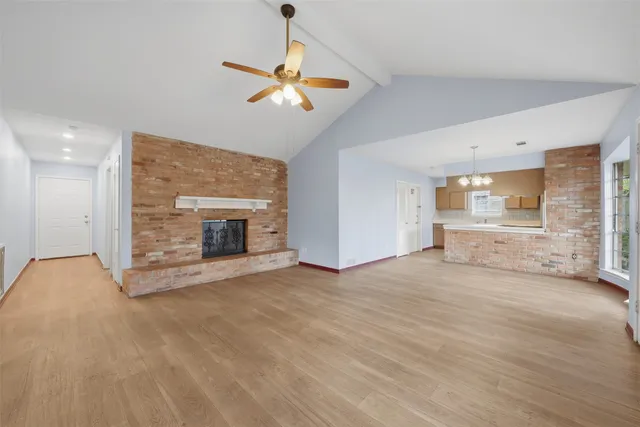 a view of an empty room with a fireplace and a chandelier fan