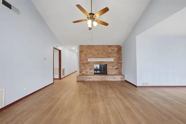 a view of empty room with wooden floor and fireplace