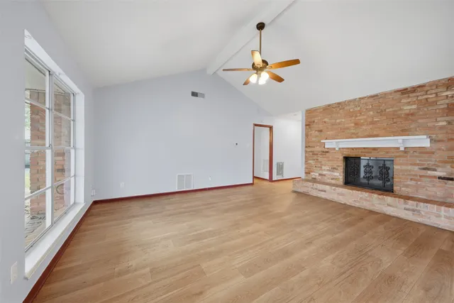 a view of an empty room with a fireplace and a window