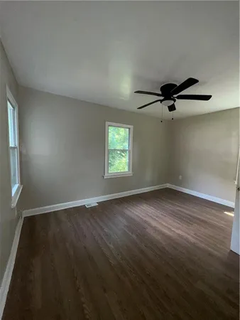 an empty room with wooden floor fan and windows