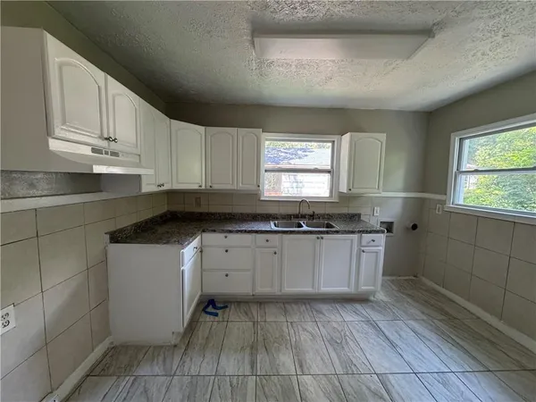 a kitchen with granite countertop a sink cabinets and window