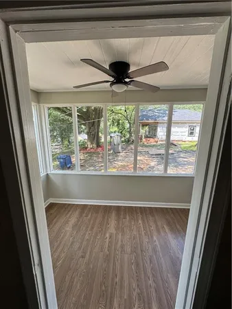 a view of empty room with wooden floor and fan