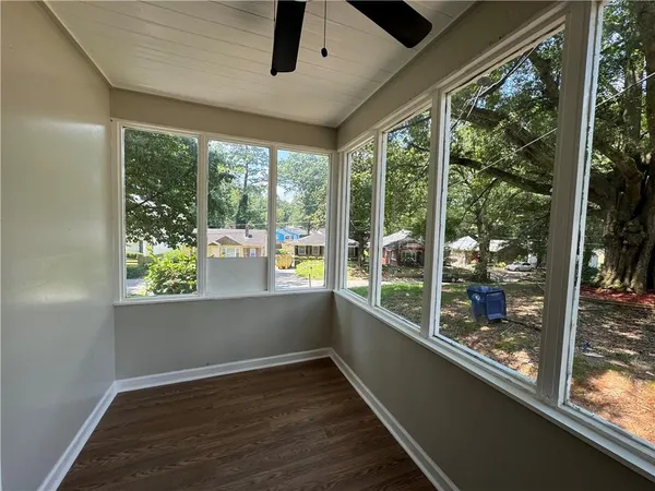 a view of an empty room with wooden floor and a window