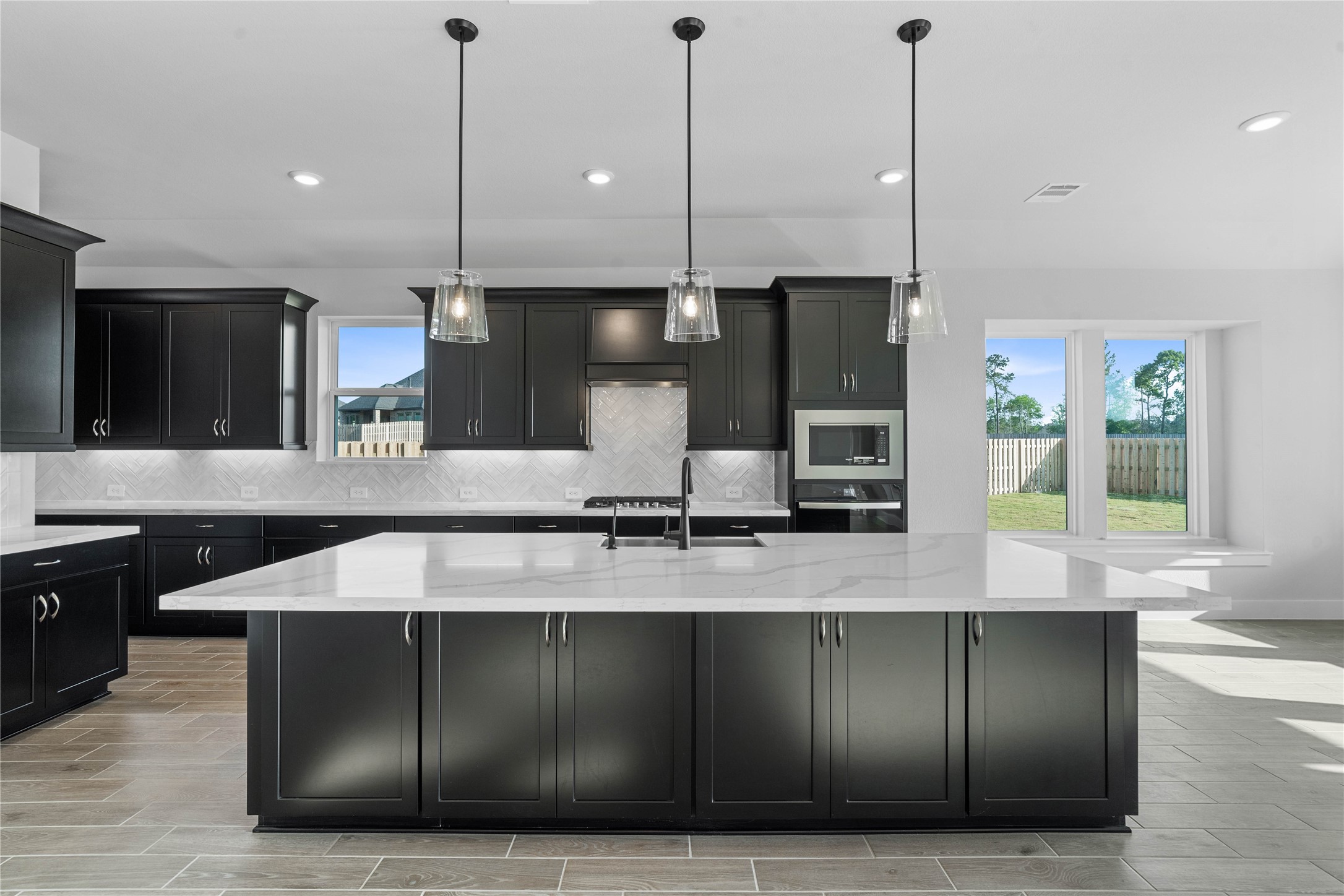 2114 Rowl Street Montgomery, TX 77316 - Photo 29 of 50 The oversized island offers generous prep and gathering space, complemented by clean-lined cabinetry, modern lighting, and warm flooring that adds a welcoming touch throughout. A perfect backdrop for hosting or relaxing at home.