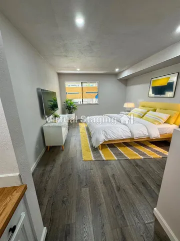 a living room with stainless steel appliances furniture and a wooden floor